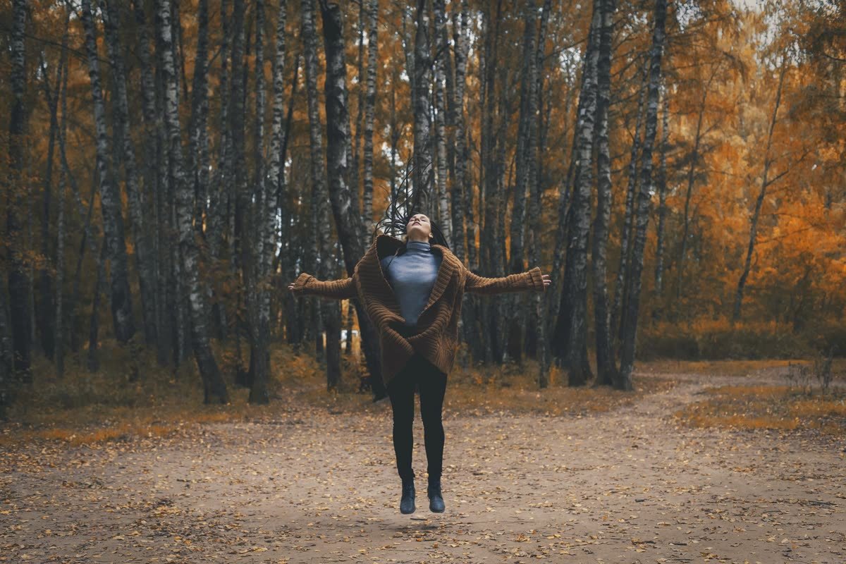 Femme libérée, bras ouverts dans une forêt d'automne